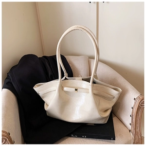 Detail of a creamy white large tote bag with glossy pleated leather and golden buckle