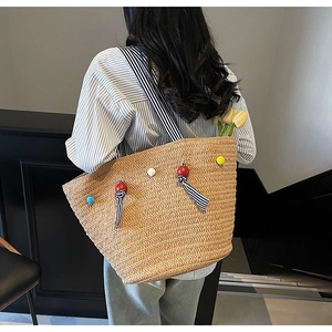 Detail of hand-woven straw tote with striped strap and colorful acrylic bead charms