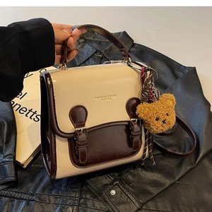 Detail of vintage beige and brown patchwork handbag with bear charm and leather texture
