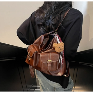 Rear view of model wearing a vintage brown faux leather backpack with multiple pockets