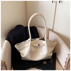 Detail of beige glossy patent leather tote bag with elegant pleats on a stylish chair