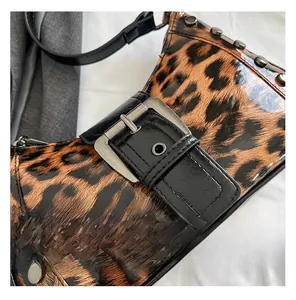 Primer plano del bolso de leopardo en charol brillante con hebillas metálicas y remaches
