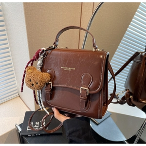 Detailed view of dark brown PU leather handbag with vintage buckle and bear charm