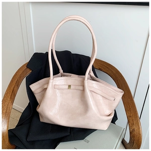 Detail of the pleated texture and golden buckle on a nude faux leather tote bag