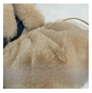 Gros plan détaillé montrant la texture douce en fausse fourrure du sac seau à cordon abricot