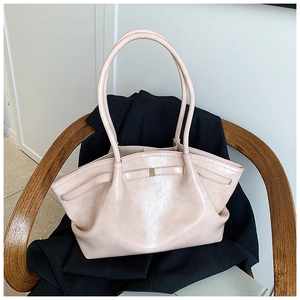 Macro detail of glossy pleated pink tote bag with gold metal accents on a black coat
