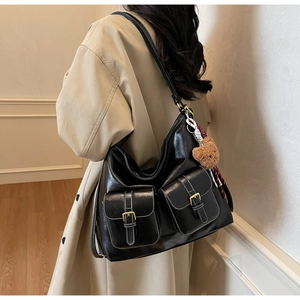 Detail of black faux leather tote bag with white contrast stitching and bear charm