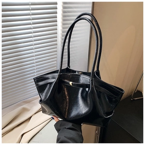 Close-up of shiny black leather tote bag with natural texture and gold buckle detail