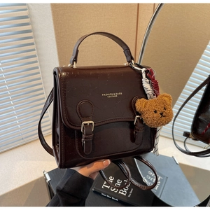 Close-up of vintage dark brown faux leather handbag with cute bear charm and gold logo