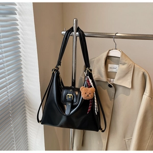 Close-up of black PU leather hobo bag with gold buckle and teddy bear pendant