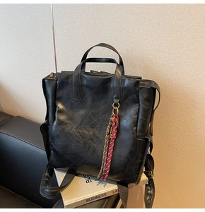 Détail d'un sac à dos vintage en cuir PU noir avec pompons tressés marron
