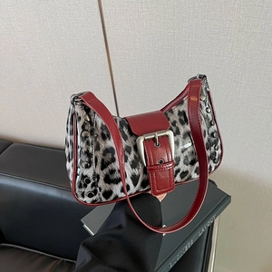 Detalle de bolso leopardo con ribete de charol rojo y remaches metálicos plateados