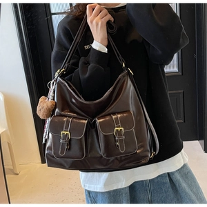 Detail of dark brown leather tote bag showing front flap pockets and cute bear charm