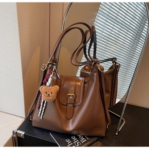 Close-up of vintage brown tote bag featuring a leather strap buckle and plush bear charm