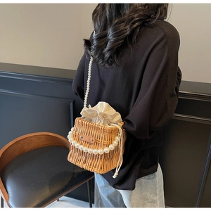 Detail of hand-woven bucket bag with pearl handle and soft fabric drawstring lining