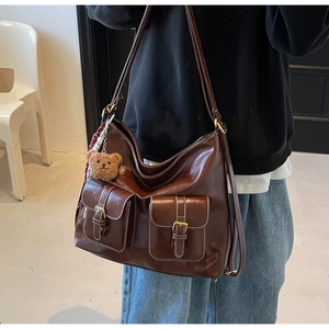Detailed close-up of brown PU leather bag with white contrast stitching and dual pockets