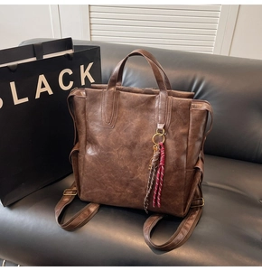 Vue détaillée d'un sac à dos vintage en cuir marron avec pendentif anneau tissé sur canapé