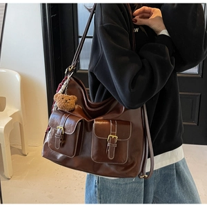 Detail view of a vintage brown leather tote bag featuring functional front buckle pockets