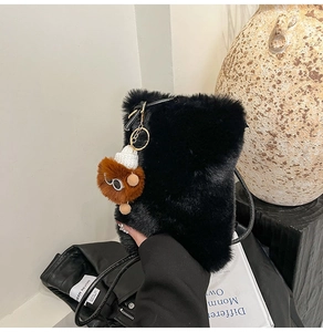 Détail d'un sac à main noir en fausse fourrure avec charm en peluche et bandoulière fine