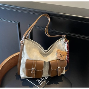 Detailed view of canvas tote with leather pockets and cute teddy bear pendant