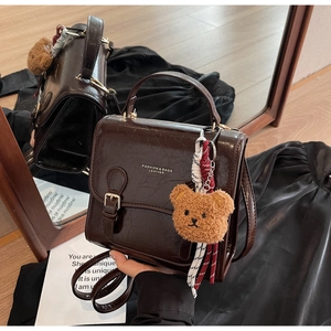 Detail of vintage brown leather square handbag with plush bear charm and long strap