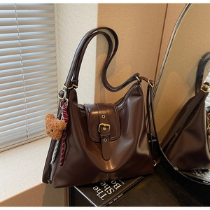 Macro view of vintage brown hobo bag with gold hardware and plush bear charm detail