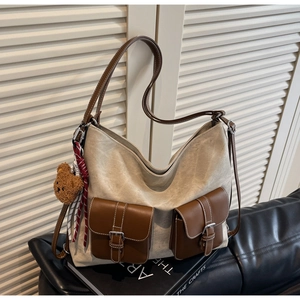Detail of vintage canvas tote with leather pockets and cute plush bear charm on a sofa