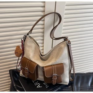 Detail view of large canvas hobo bag with brown leather pockets and plush bear charm