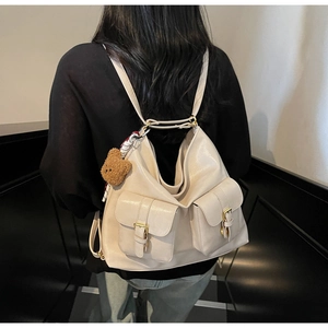 Detail view of cream vintage tote bag with two front pockets and golden metal buckles