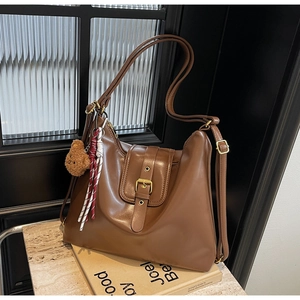 Detail of vintage brown leather hobo bag with metal buckle and plush bear charm