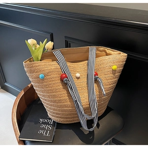 Detailed close-up of woven straw tote bag with colorful beads and striped handles
