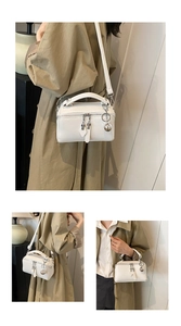 Close-up of white lychee pattern crossbody bag with silver ball charm and dual zippers