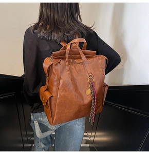 Sac à dos vintage en cuir marron avec breloque raquette de tennis et pompon décoratif