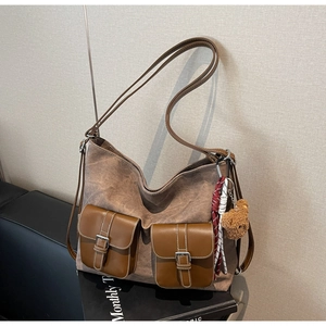 Close-up of vintage brown canvas tote bag with leather pockets and a cute bear charm