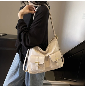 Detail of a beige multi-pocket leather hobo bag worn by a model in an indoor setting