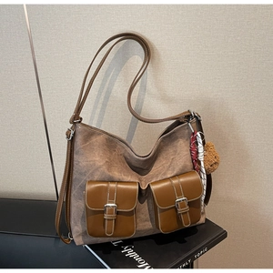 Close-up of vintage brown canvas tote bag with front leather pockets and bear charm detail