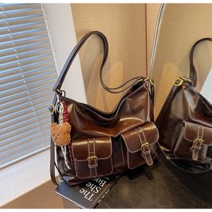 Detail of dark coffee leather tote bag with white stitching and plush bear charm