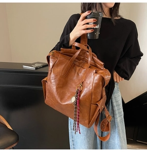 Détail d'un sac à dos vintage en cuir marron avec pompon sur une table de café