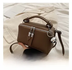 Detail of a brown vintage Boston bag featuring dual silver zippers and a metal ball charm
