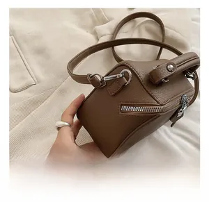 Detail view of brown pebbled leather square bag with silver metal hooks and strap