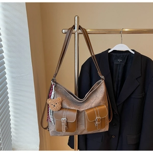Detail view of coffee brown faux suede tote bag with front buckle pockets and plush charm