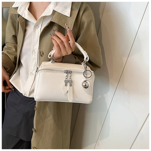 Detailed close-up of white lychee grain leather handbag with silver ball charm detail