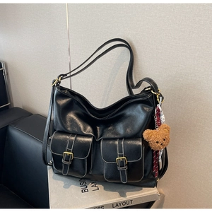Detail of black large capacity leather tote bag with multi-pockets and teddy bear charm