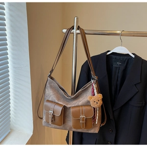 Detail of vintage brown large capacity shoulder bag with double pockets and bear keychain