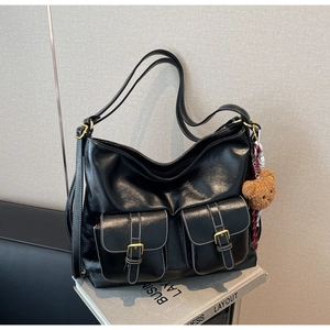 Detail of black leather hobo bag featuring two functional pockets with gold buckles