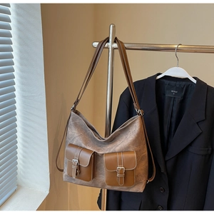 Close-up of vintage brown leather tote bag with two front flap pockets and metal buckles
