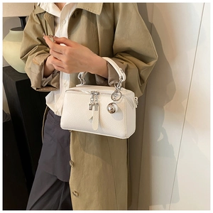 Detail of white textured leather Boston bag with silver sphere pendant and dual zipper design