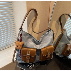 Detailed view of grey canvas tote with brown leather pockets and plush bear charm