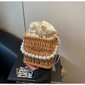 Detailed view of woven straw bucket bag with large pearl handle and canvas liner