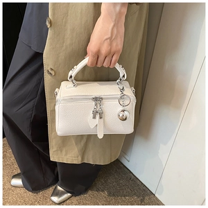 Detail of white lychee leather handbag with double zippers and silver ball pendant